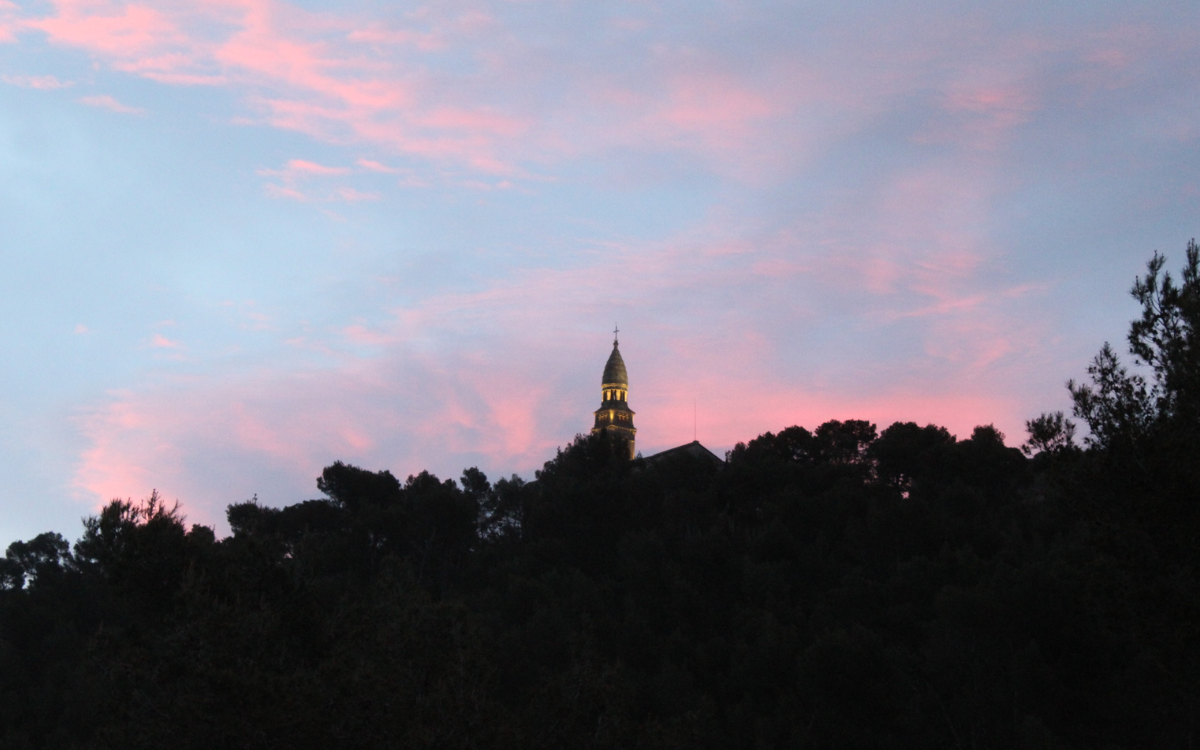 The peak of a church against a cotton candy sky in Provence, France.
